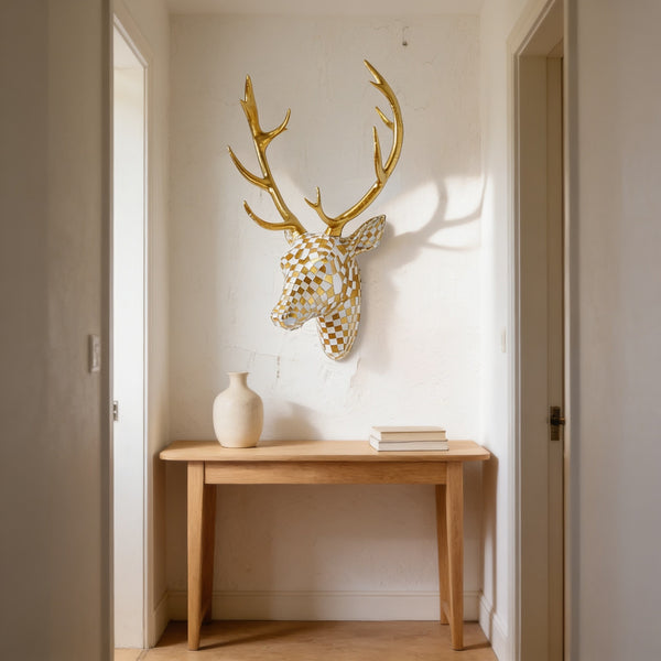 Gold and cream mosaic resin deer head with gold antlers mounted on a hallway wall above a console table.