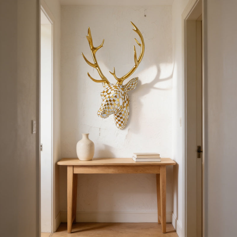 Gold and cream mosaic resin deer head with gold antlers mounted on a hallway wall above a console table.