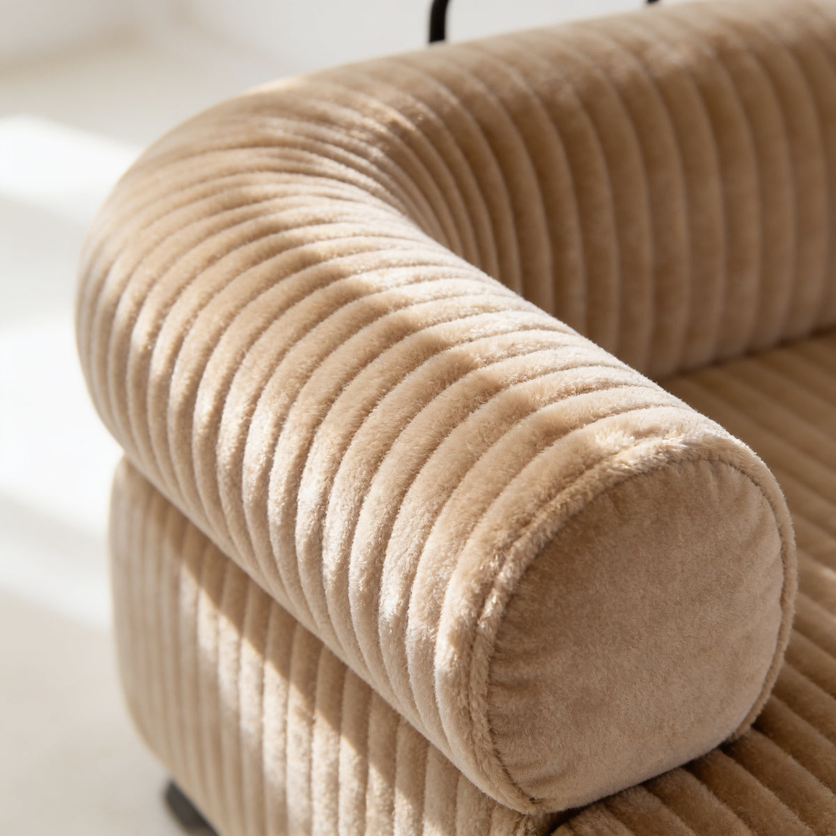 Macro detail of the wide-wale beige corduroy over the curve of a bolster arm, each rib about one centimetre across.