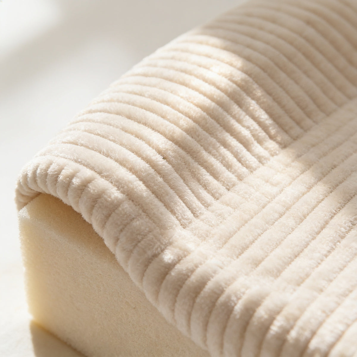 Macro detail of the wide-wale beige corduroy upholstery, each rib about one centimetre across.