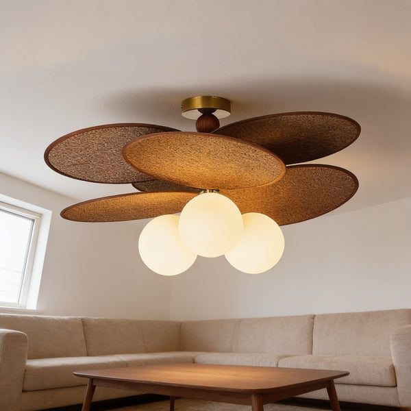 Woven leaf flush-mount ceiling light with three glowing opal globes above a living room sofa.