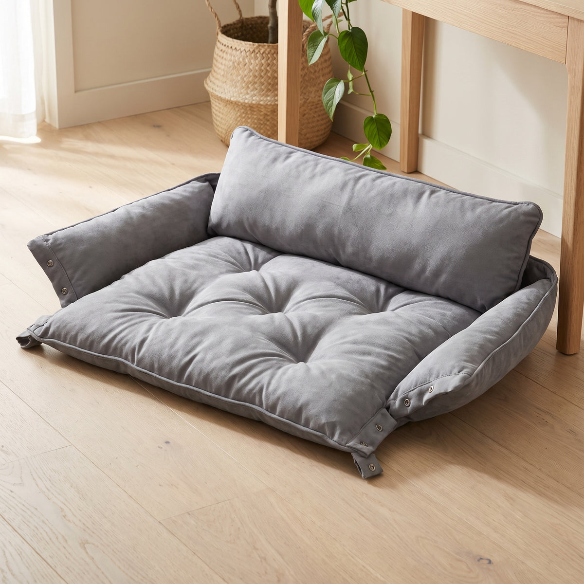 Gray convertible pet bed opened out flat into its low sofa shape on a wooden floor