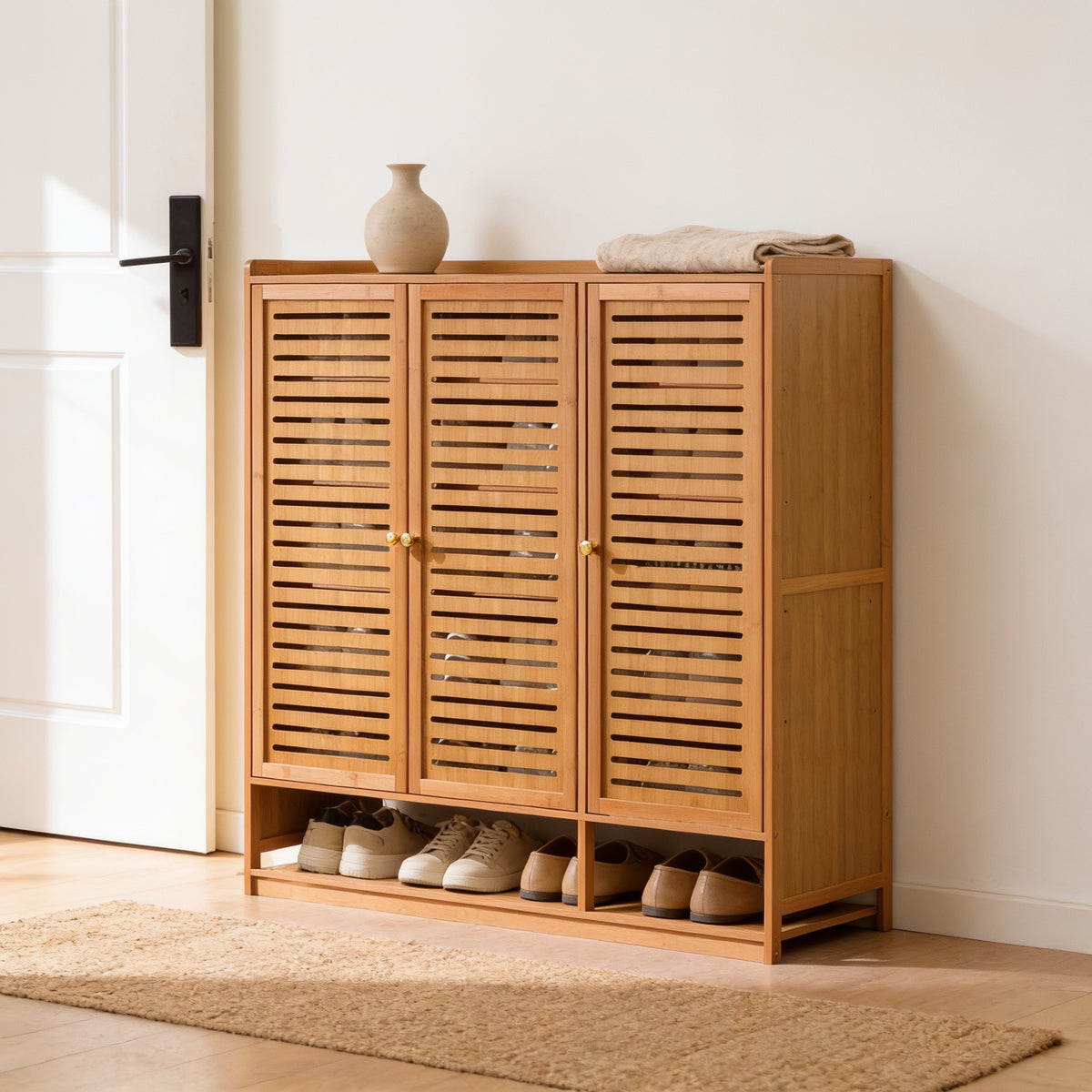Three-door bamboo-frame shoe cabinet with slotted doors, 93 cm tall, beside a white door in a bright entryway