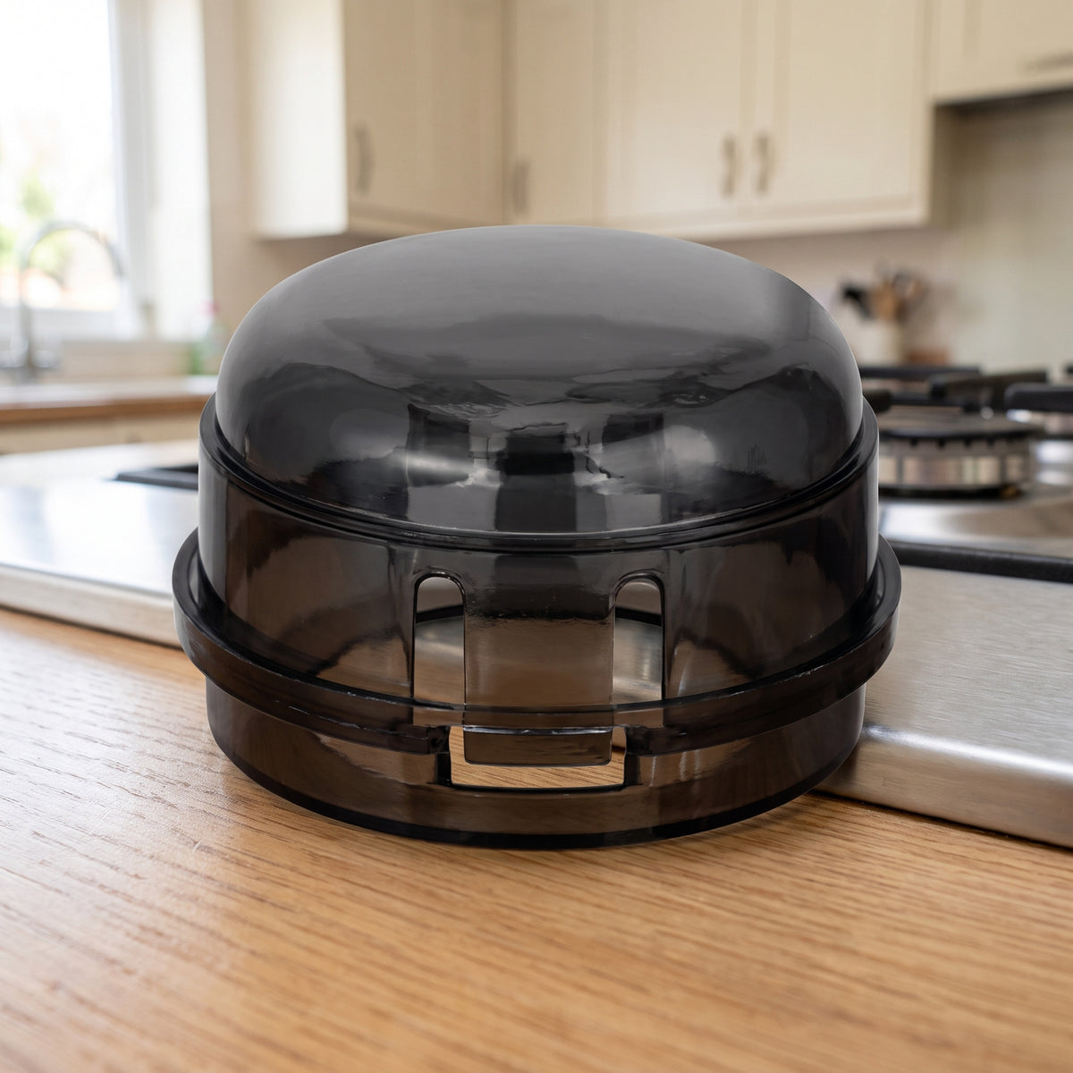 One smoke-black stove knob cover on a light oak kitchen countertop