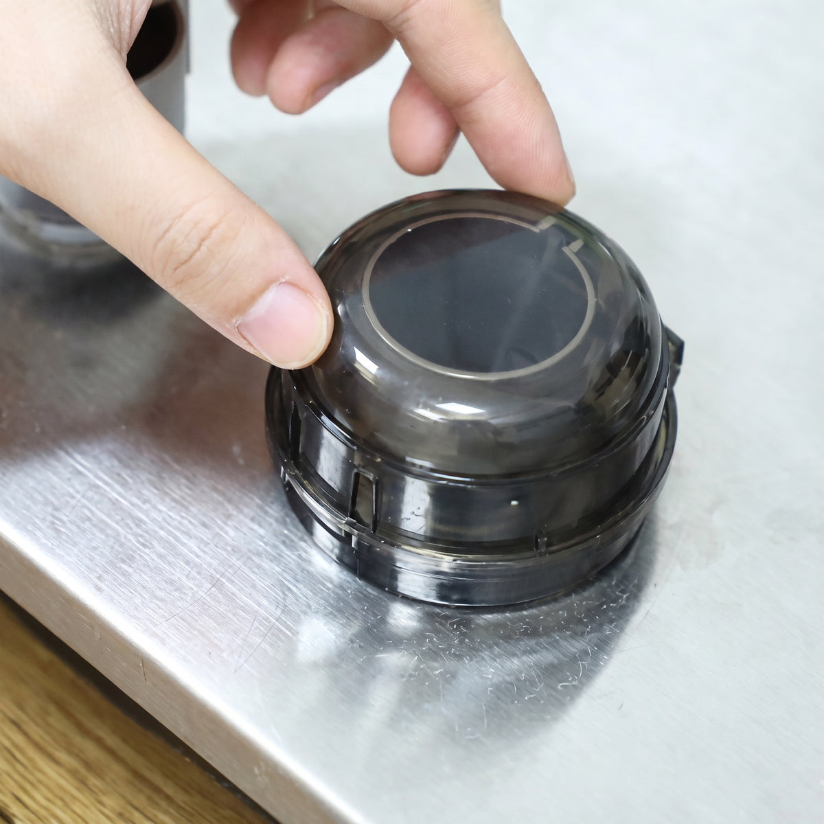 Hand pressing a stove knob cover's lid shut over the knob
