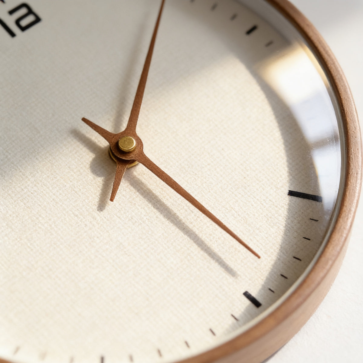 Close-up of the cream dial, brass centre cap and tan hands of the wooden wall clock