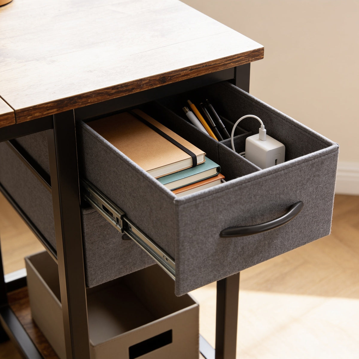 Close view of the fabric drawer pulled open in the desk tower, holding notebooks, pens and a charger.