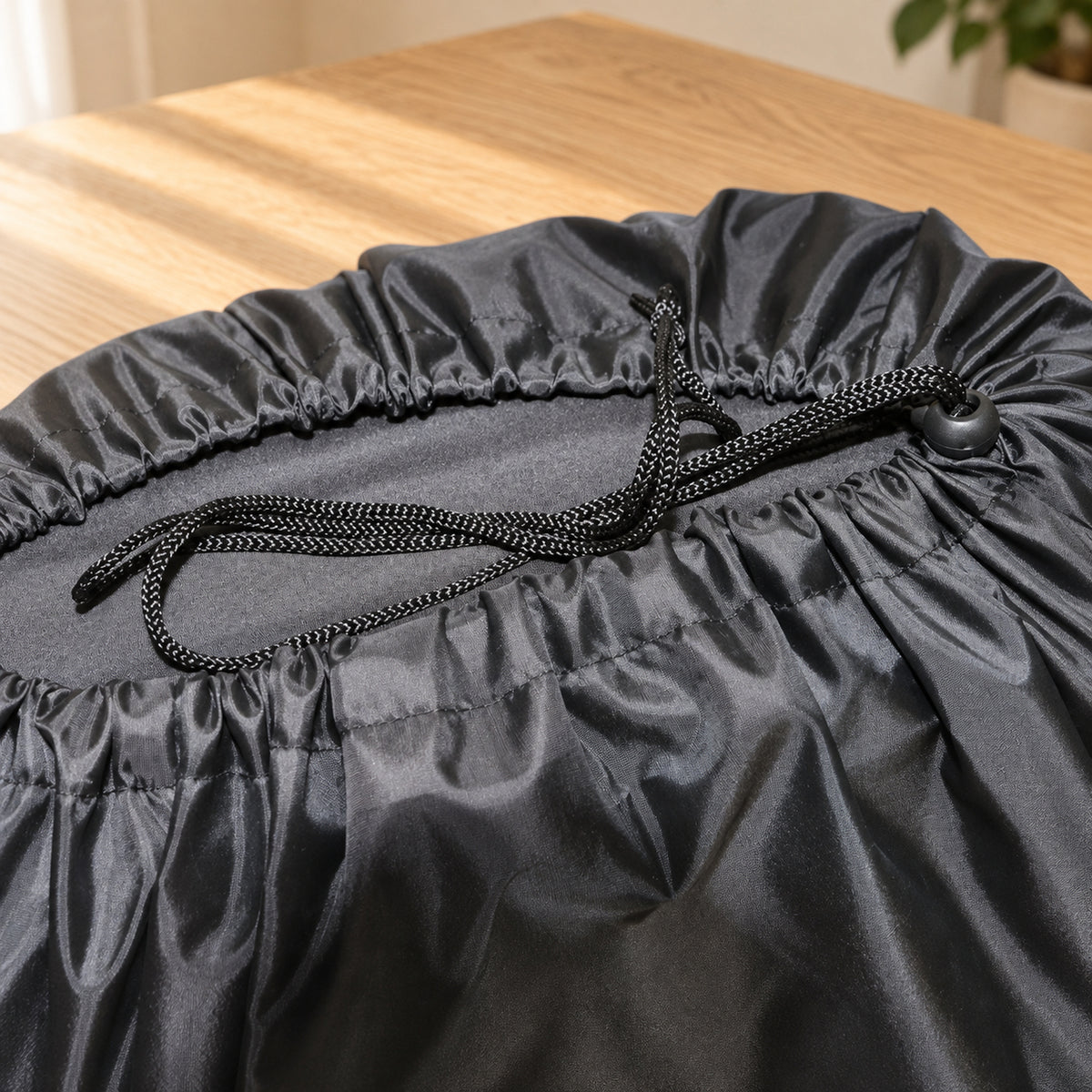 Close-up of the travel bag's gathered mouth, braided drawstring and black sliding cord lock