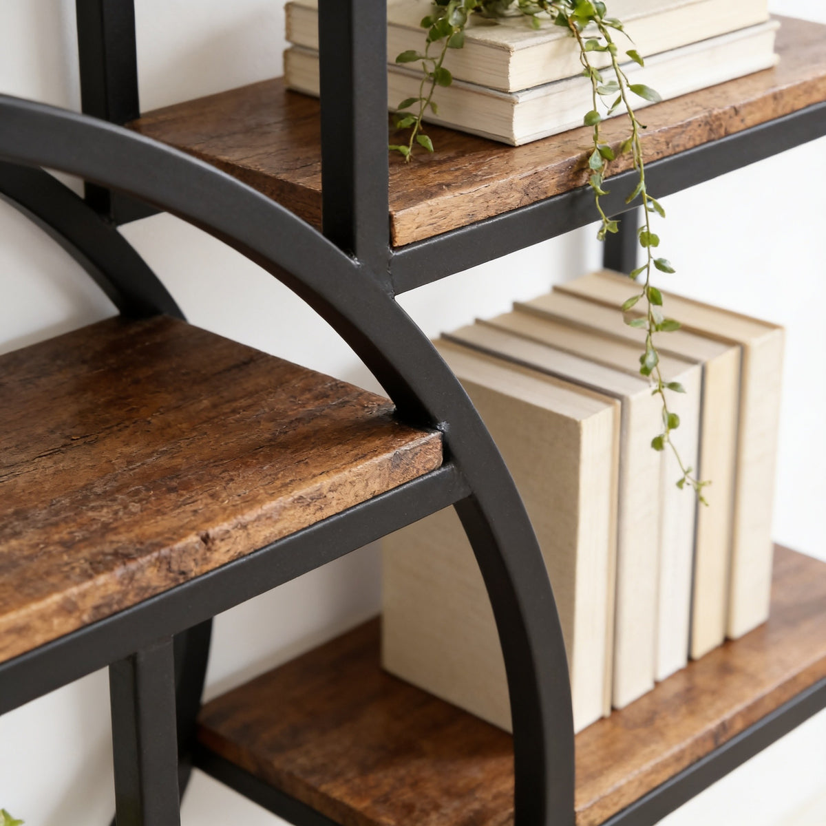 Close detail of the curved black iron arc meeting a rustic brown wood-grain shelf.