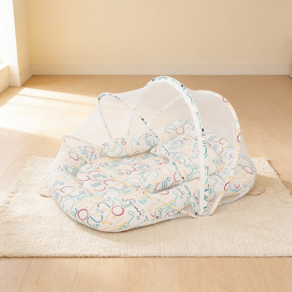 Safari Outline foldable travel bassinet, white cotton with blue and red line-drawn shapes, with its mesh net dome up on a cream rug in a bright living room