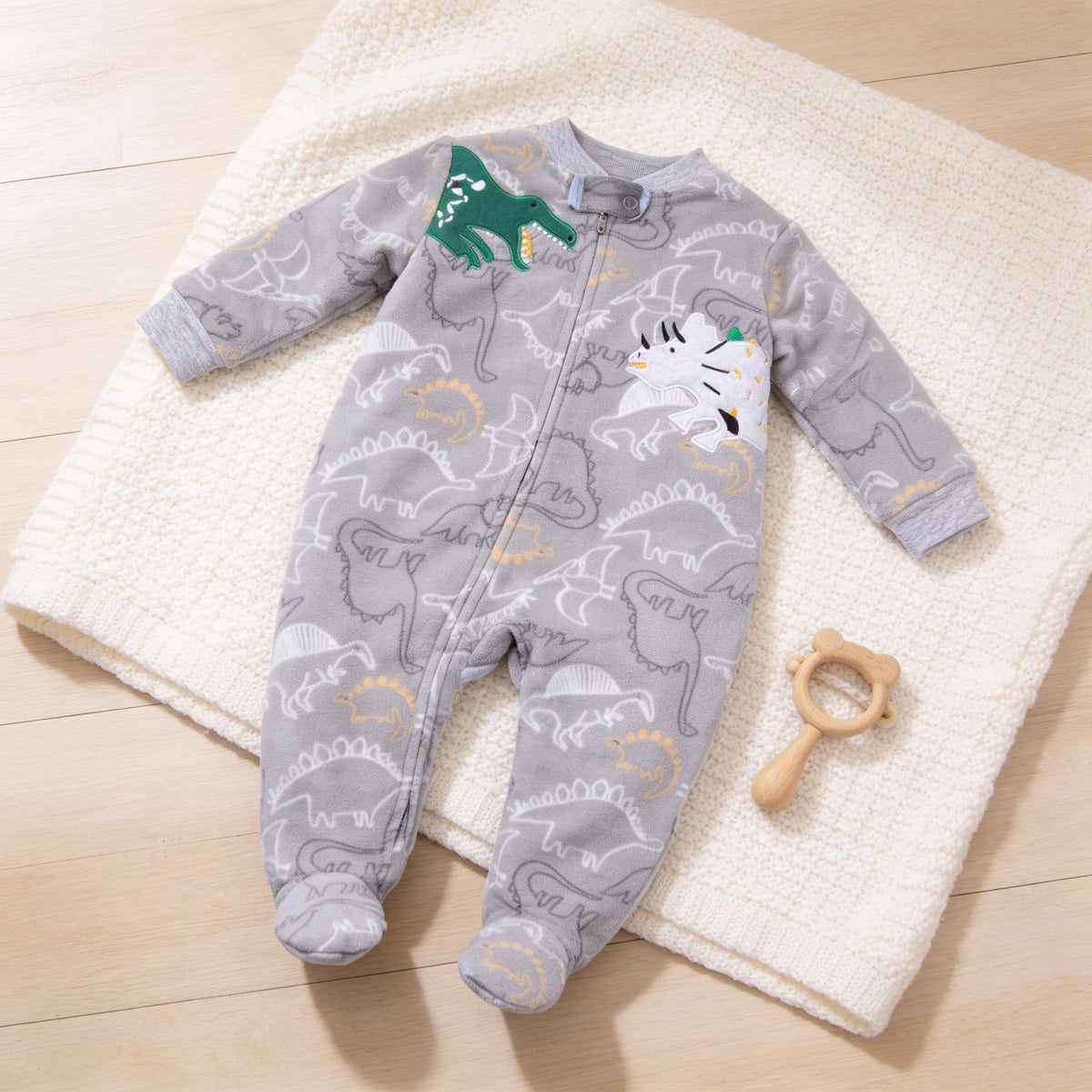 Gray Dinosaur fleece zip-up baby footie pajamas, gray with dinosaur print, laid flat.