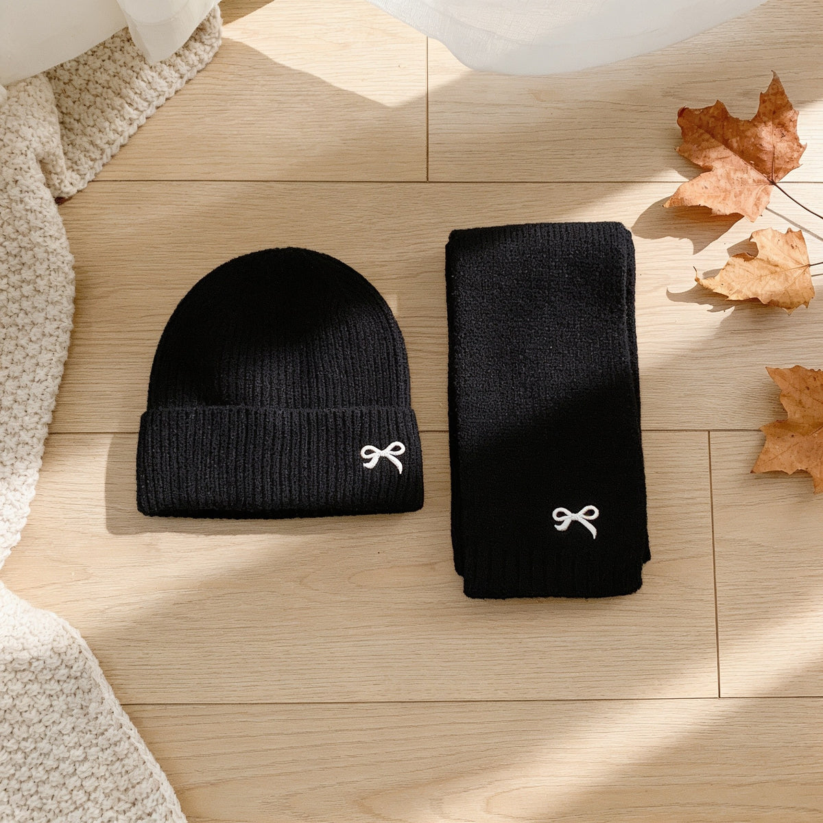 Black ribbed knit kids hat and scarf set with embroidered bows.
