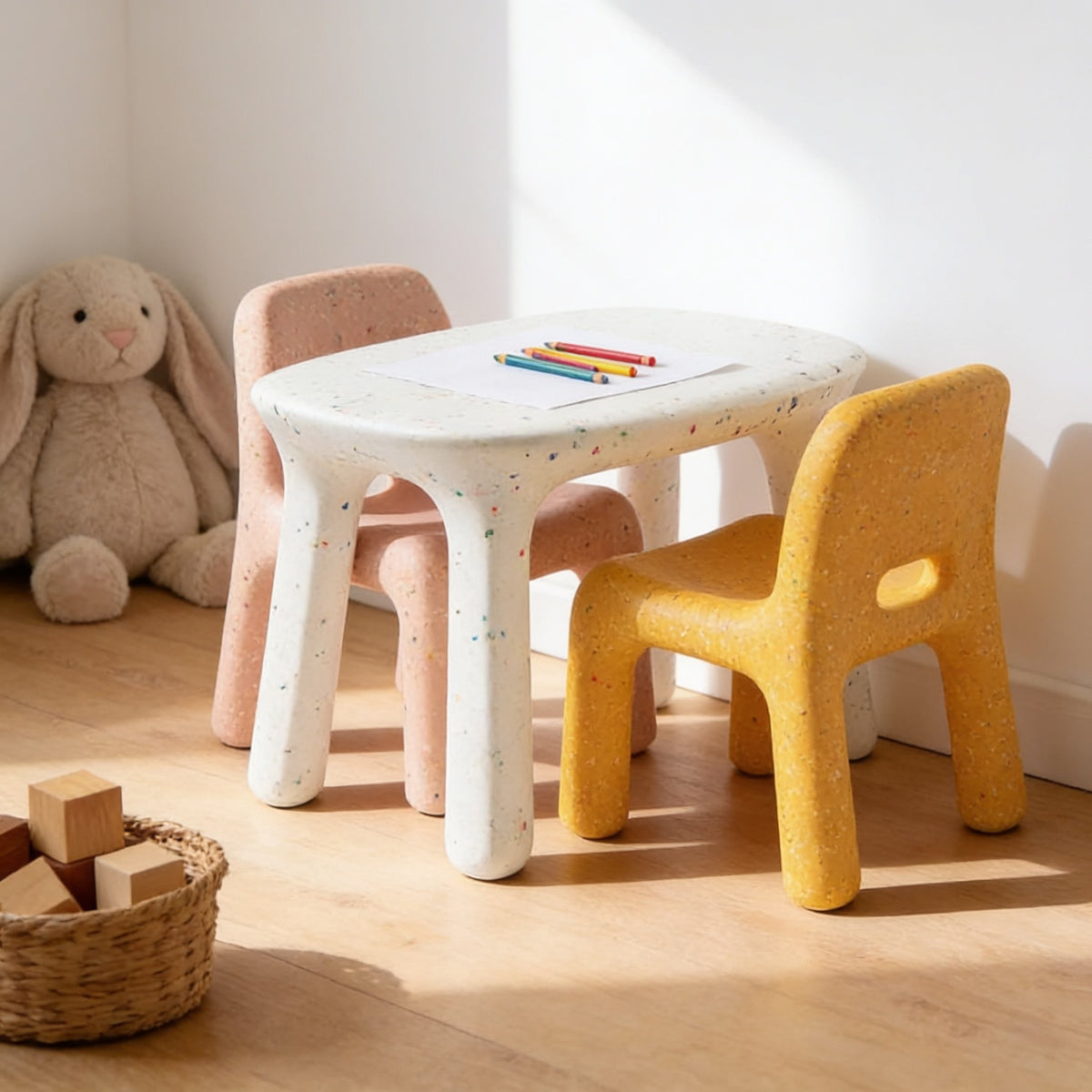 White speckled kids table with dusty pink & yellow speckled chairs in a sunny kids room.