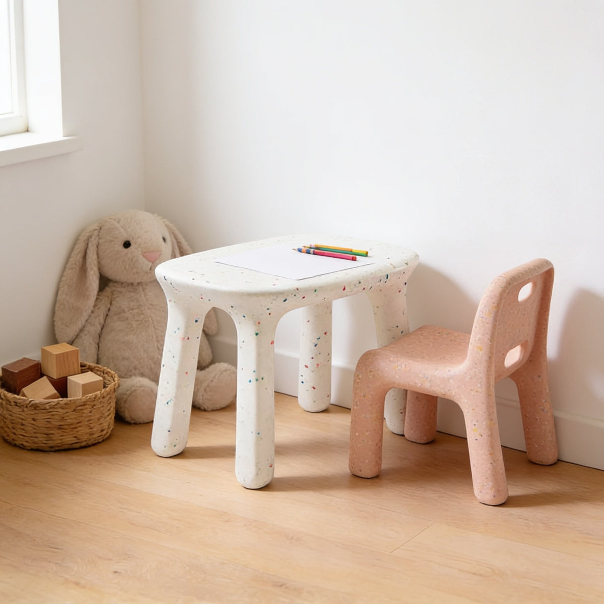 White speckled kids table with dusty pink speckled chair in a sunny kids room.