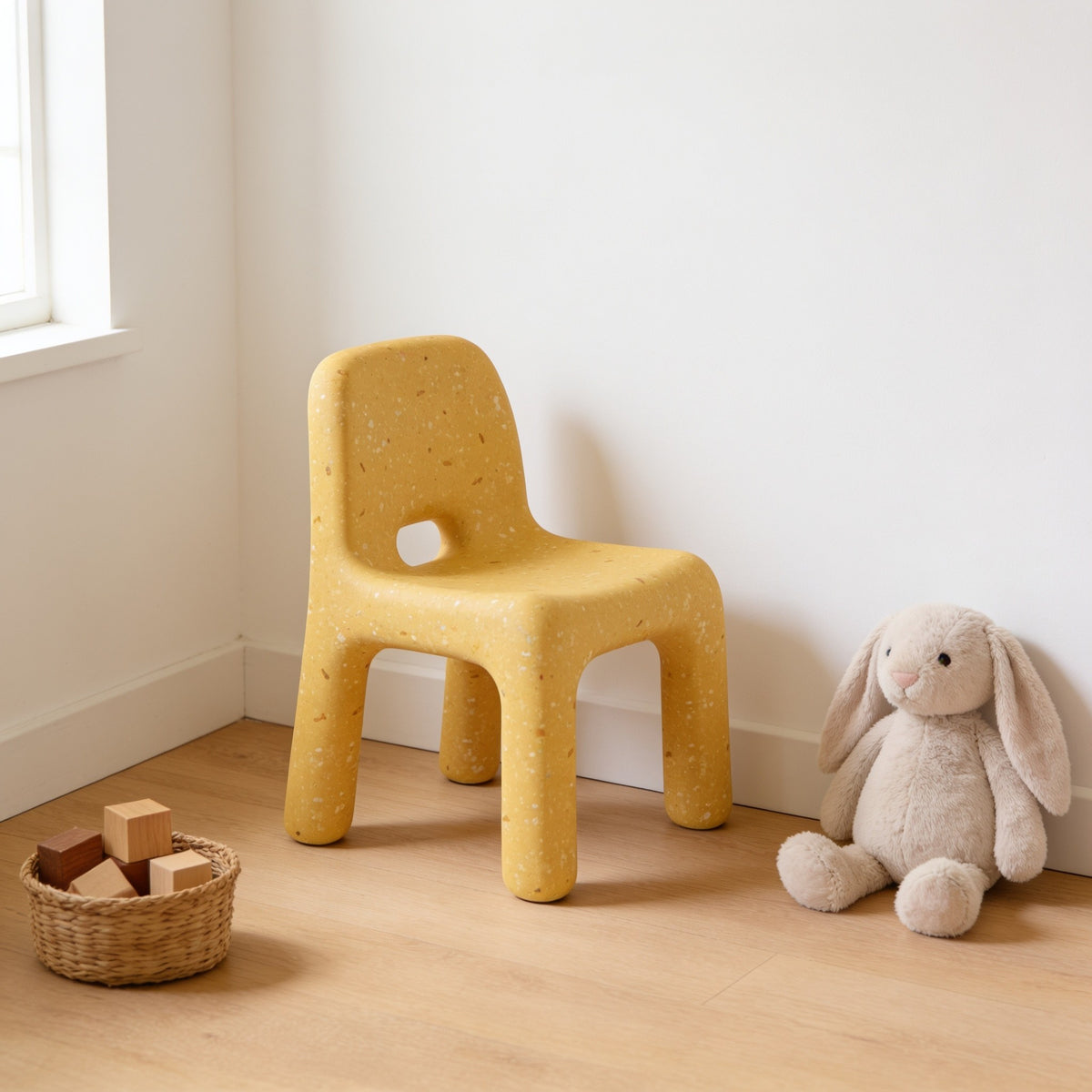 Yellow speckled molded kids chair with a hand-hole backrest in a sunny kids room.