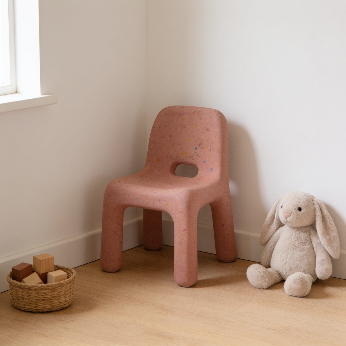 Dusty Pink speckled molded kids chair with a hand-hole backrest in a sunny kids room.