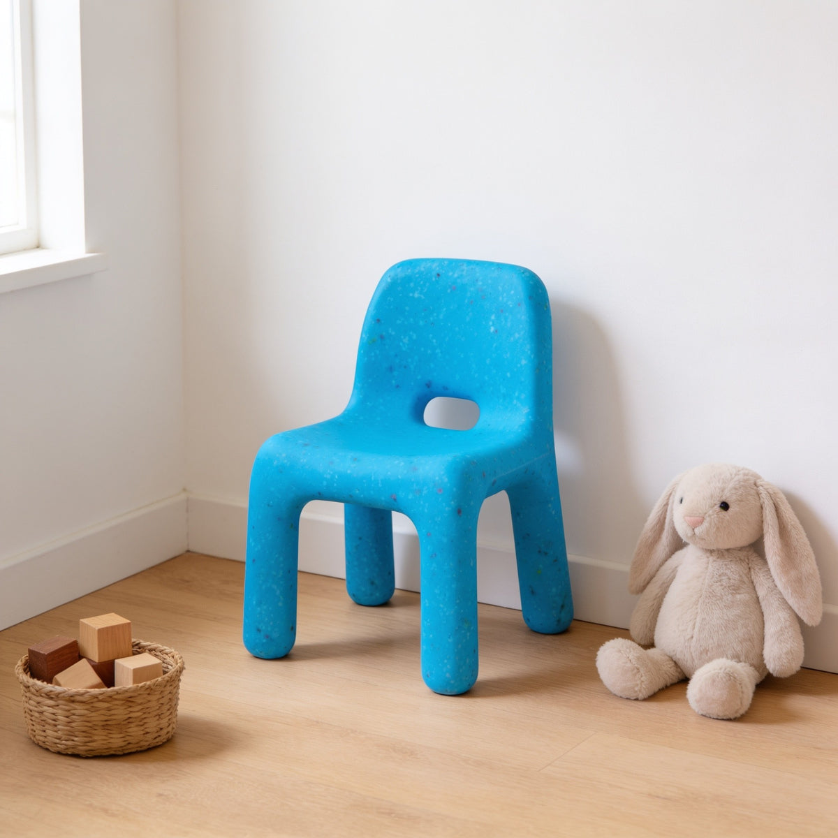 Blue speckled molded kids chair with a hand-hole backrest in a sunny kids room.