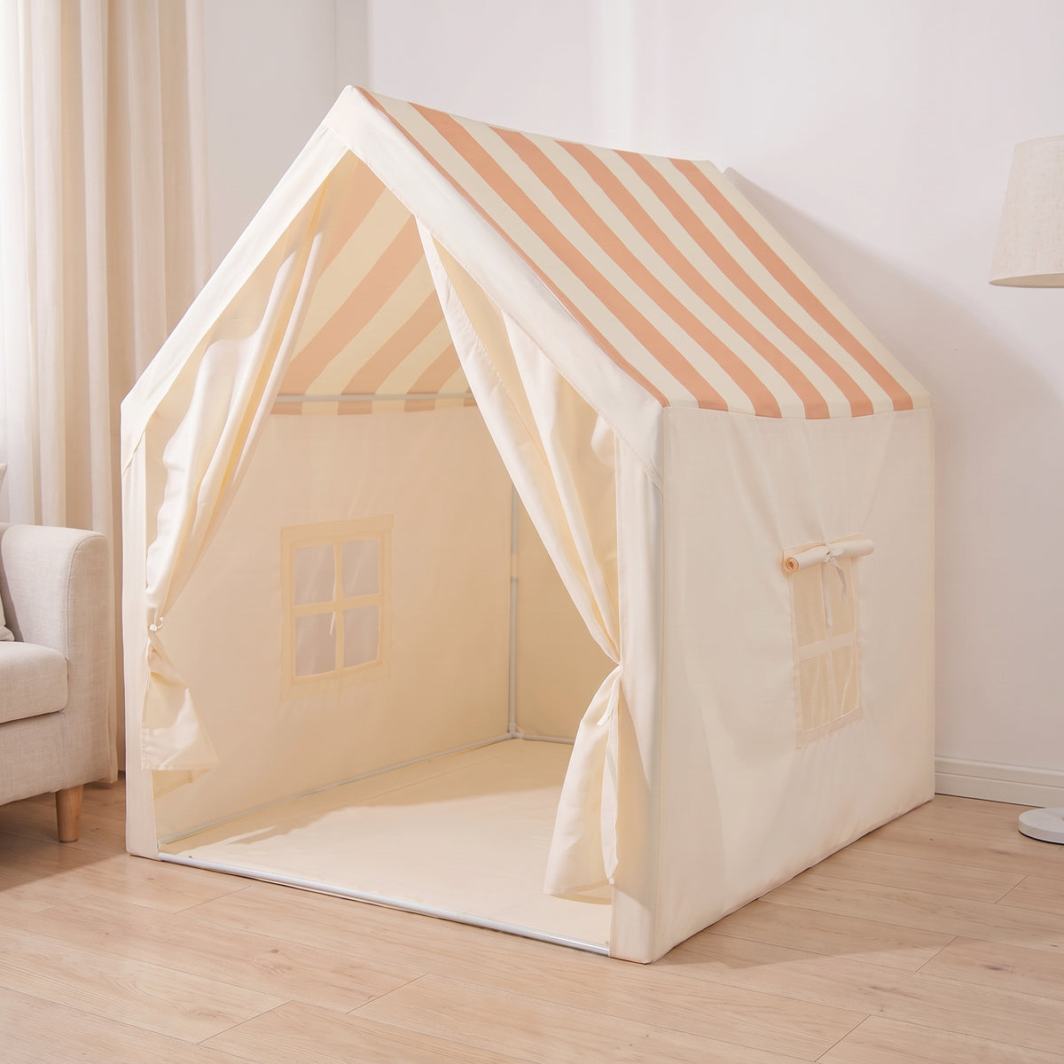 Striped-roof play tent standing in a living-room corner beside a linen sofa