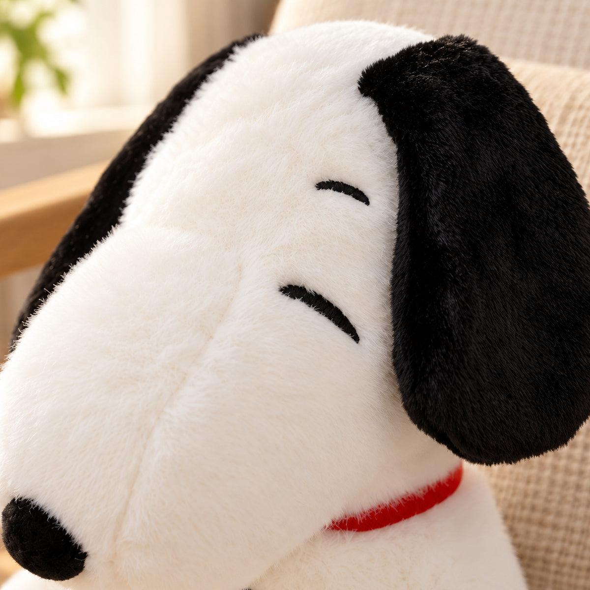 Close-up of black plush ear and curved eye embroidery against the puppy white fur
