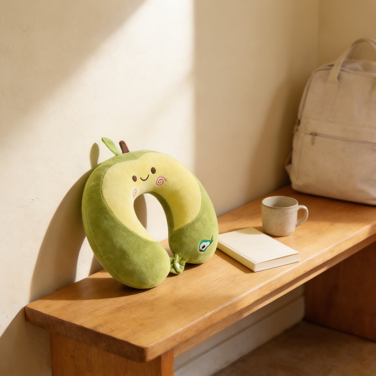 Green avocado memory foam travel neck pillow resting on a light oak entryway bench beside a packed canvas bag