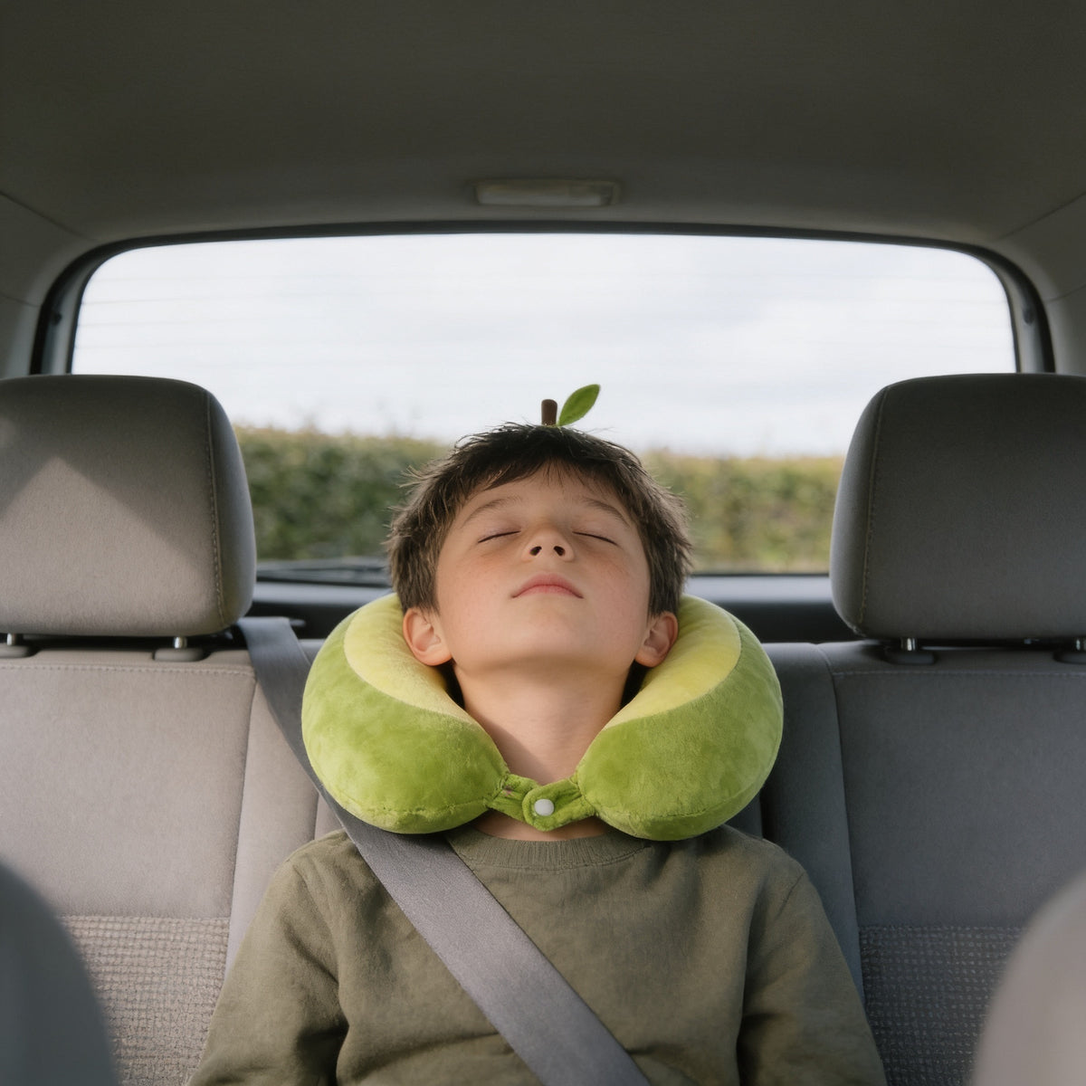 Child resting in a car back seat wearing the green avocado memory foam travel neck pillow