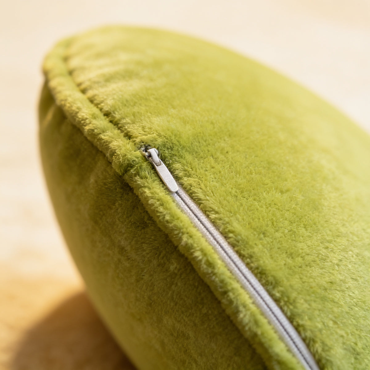 Close-up of the short-pile plush and hidden zip seam on the green avocado travel neck pillow