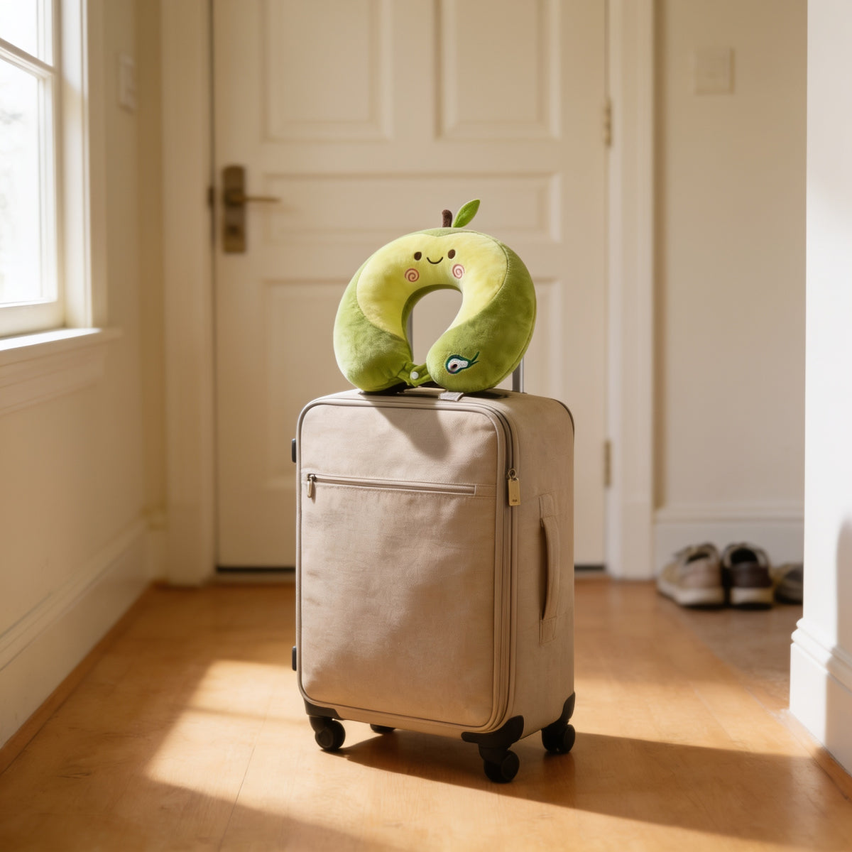 Green avocado memory foam travel neck pillow sitting on a packed carry-on suitcase in a sunlit entryway
