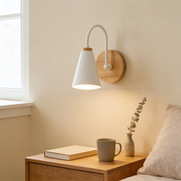 White cone wall sconce with solid wood base lit warm white above an oak nightstand with a book and cup — Nordic Wood & Metal Cone Wall Sconce