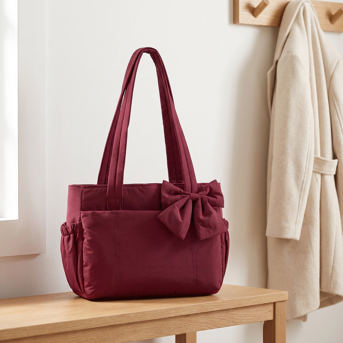 Burgundy puffer laptop tote bag with a bow on an entryway bench