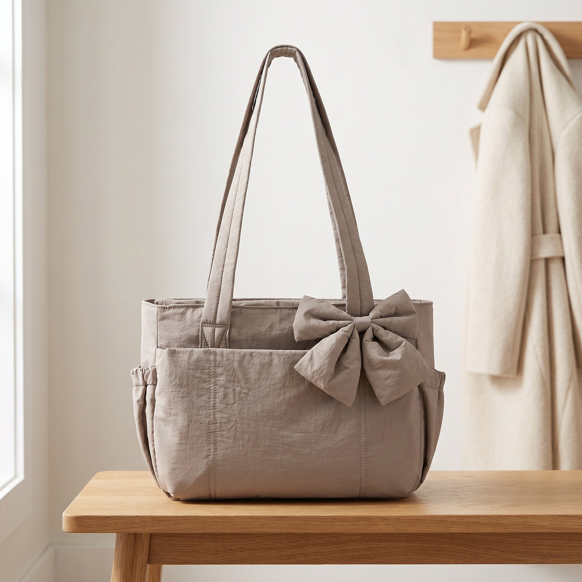 Taupe puffer laptop tote bag with a bow on an entryway bench