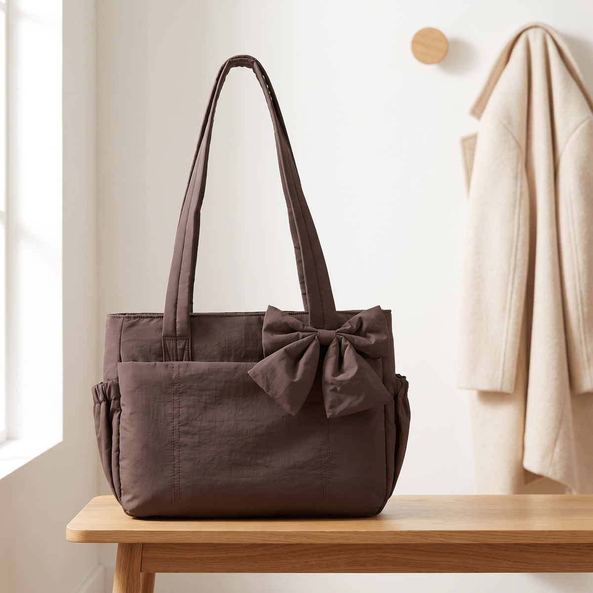 Dark brown puffer laptop tote bag with a bow on an entryway bench