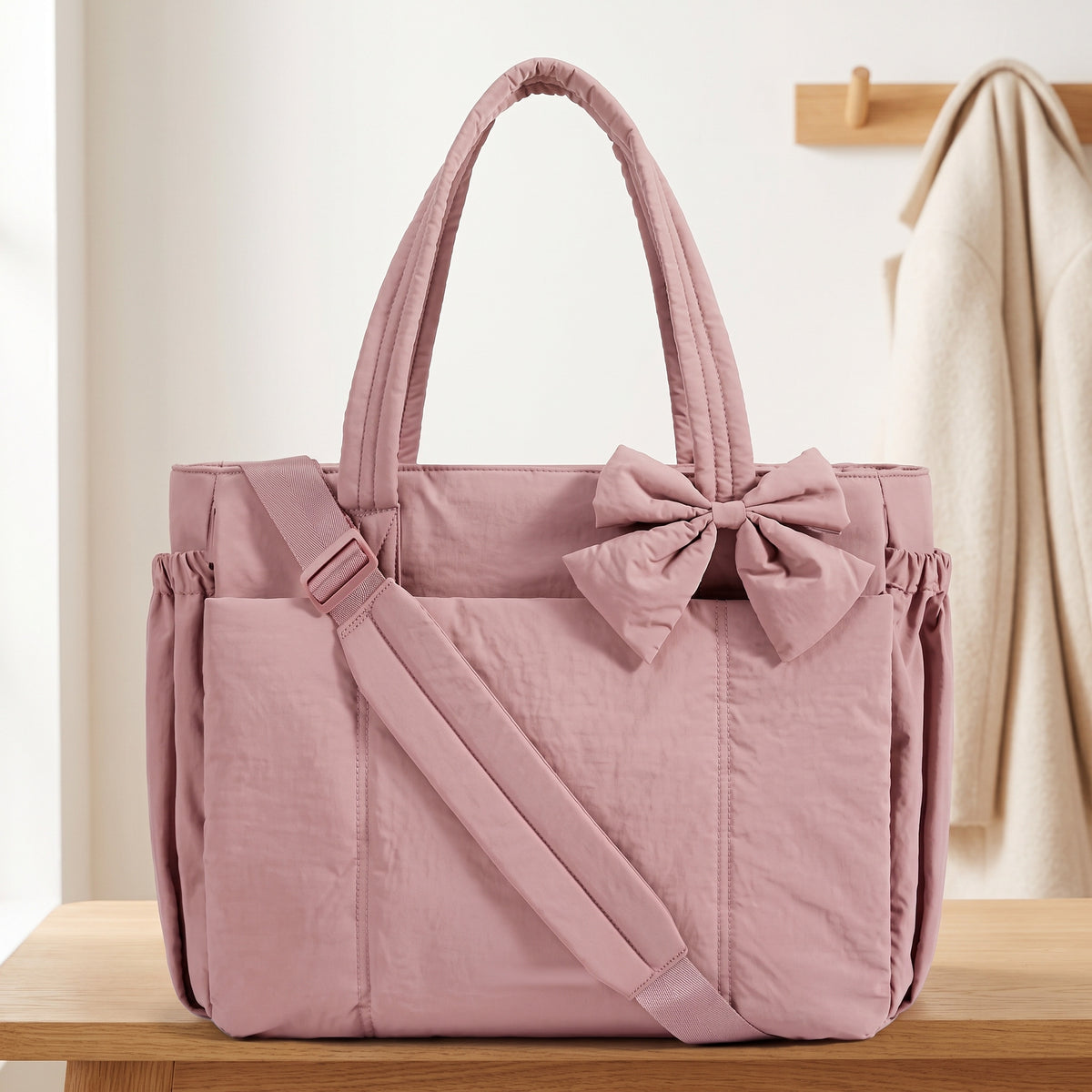 Dusty rose 15.6in puffer tote bag with its shoulder strap on an entryway bench
