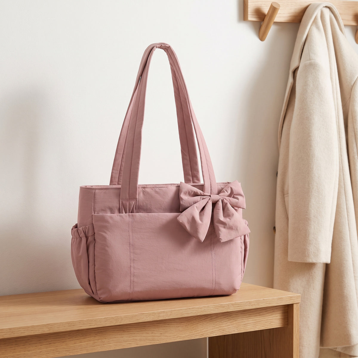 Dusty rose puffer laptop tote bag with a bow on an entryway bench