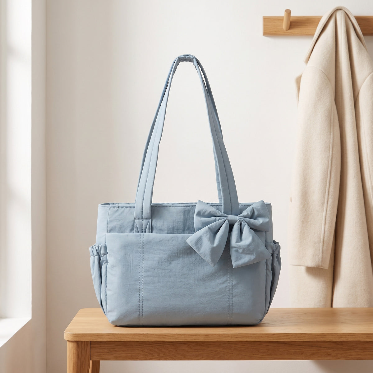Gray blue puffer laptop tote bag with a bow on an entryway bench