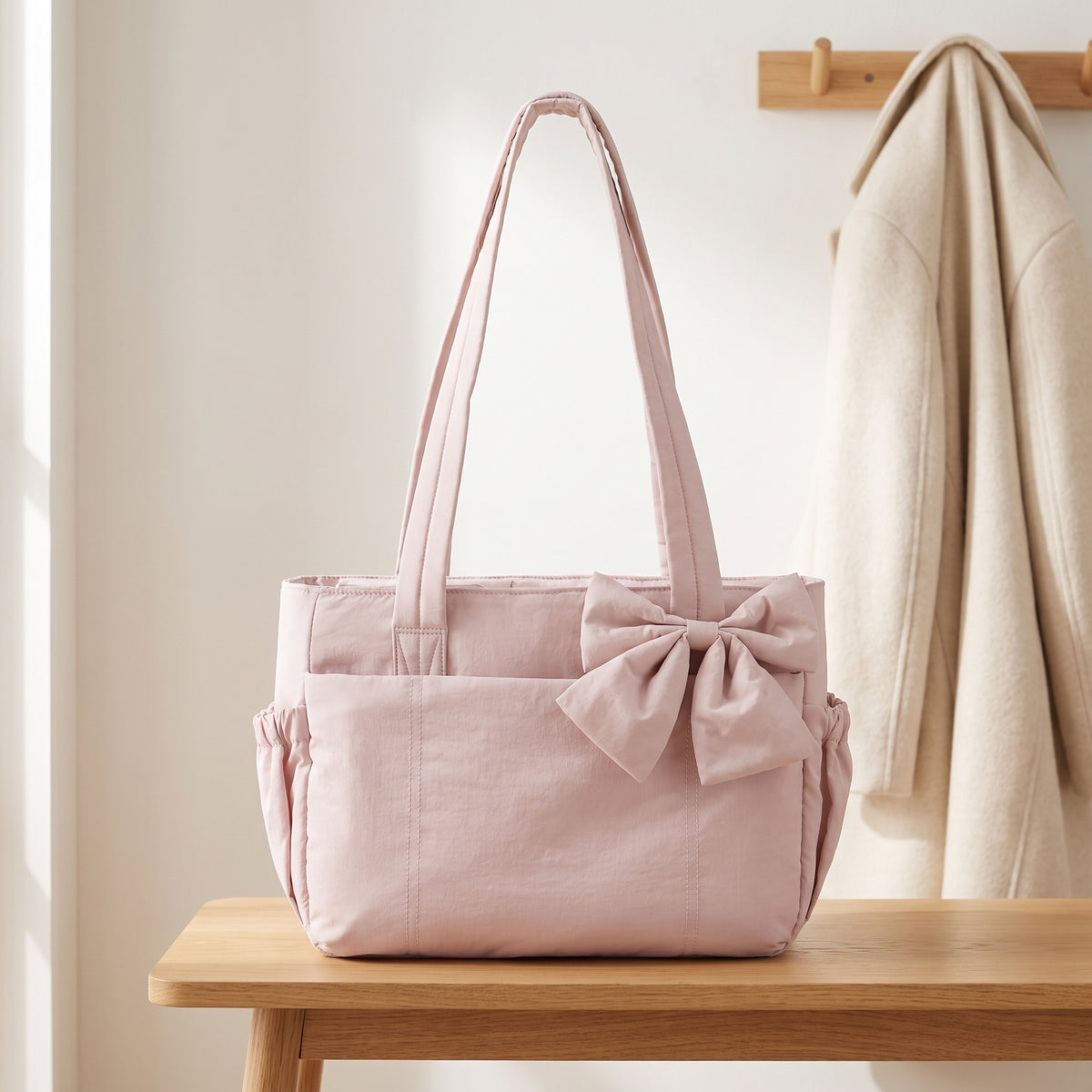 Pale pink puffer laptop tote bag with a bow on an entryway bench
