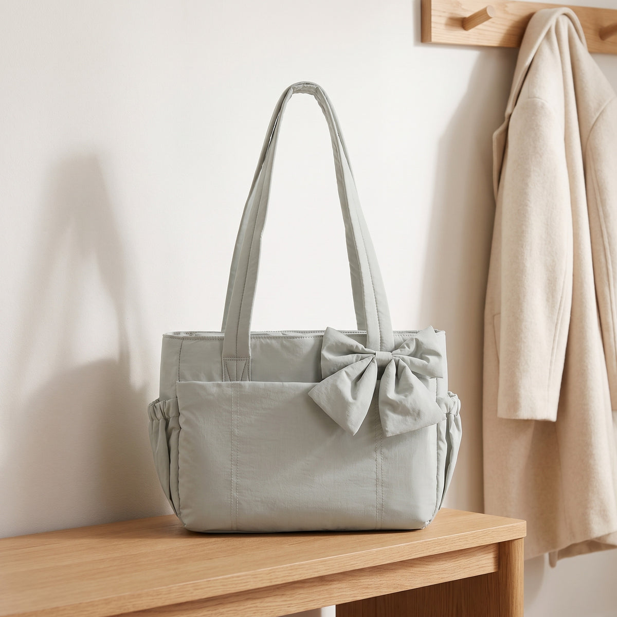 Light gray puffer laptop tote bag with a bow on an entryway bench