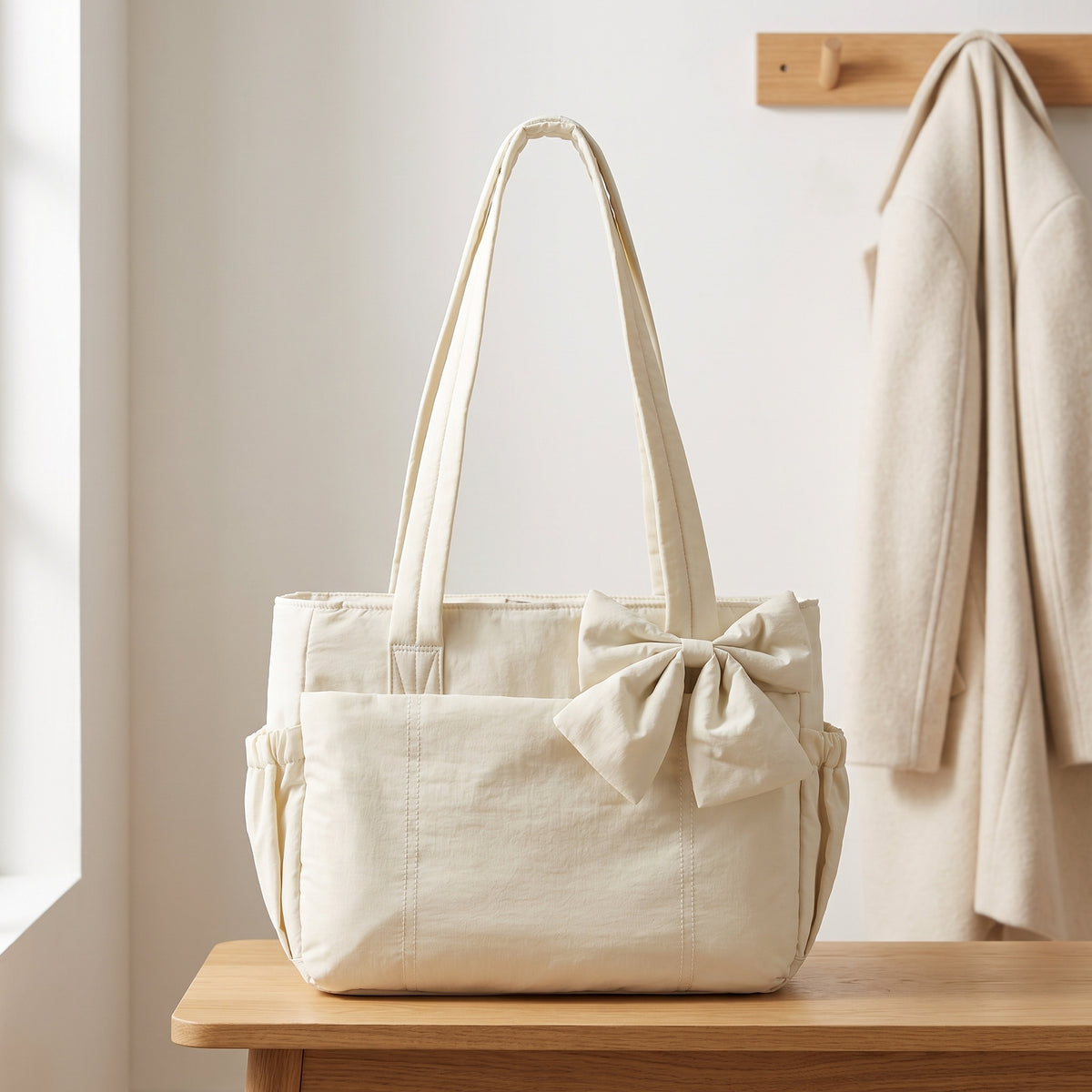 Cream puffer laptop tote bag with a bow on an entryway bench