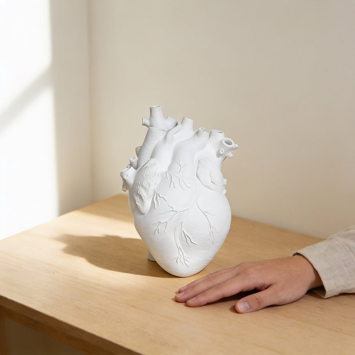 White anatomical heart vase on an oak table next to a hand for scale — Resin Anatomical Heart Vase