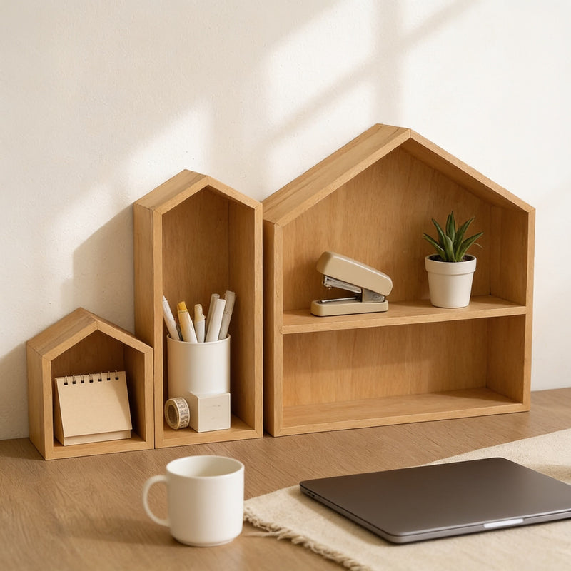 Set of three natural wood house-shaped desk shelves holding pens, a stapler and a plant on a home-office desk, 49 cm wide.