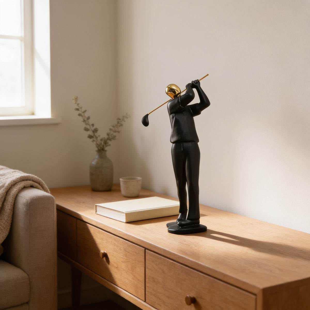 Black and gold golfer figurine styled on a light oak console beside a book and a sage stem — Black & Gold Sports Figurine