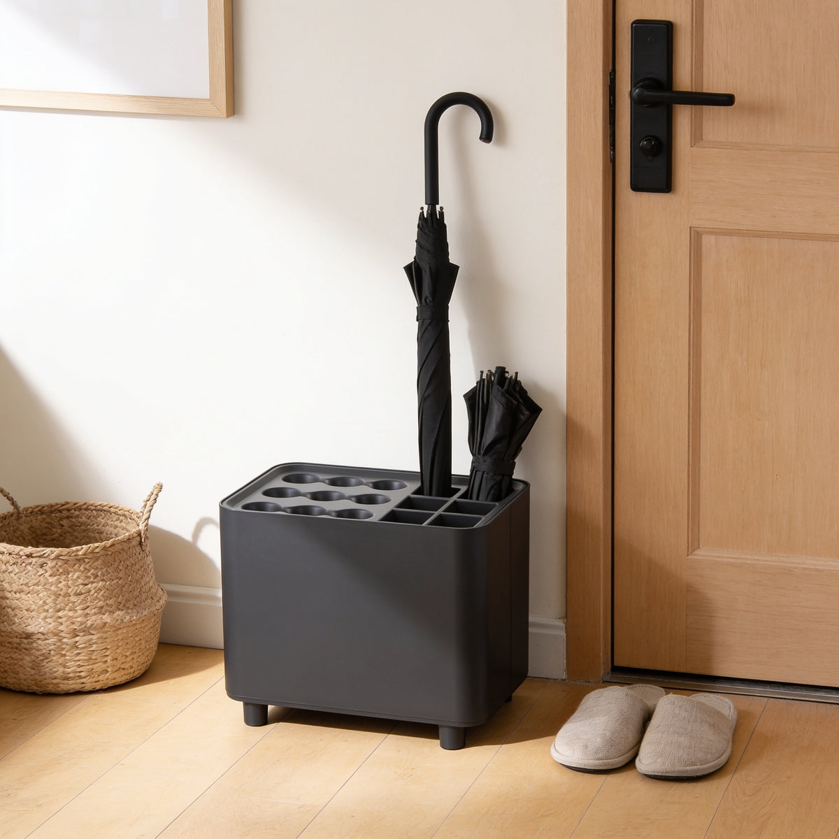Charcoal nine-slot umbrella stand with drip tray by a front door