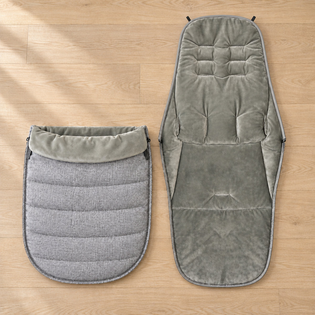 Gray footmuff back liner and detached quilted front laid side by side on an oak floor