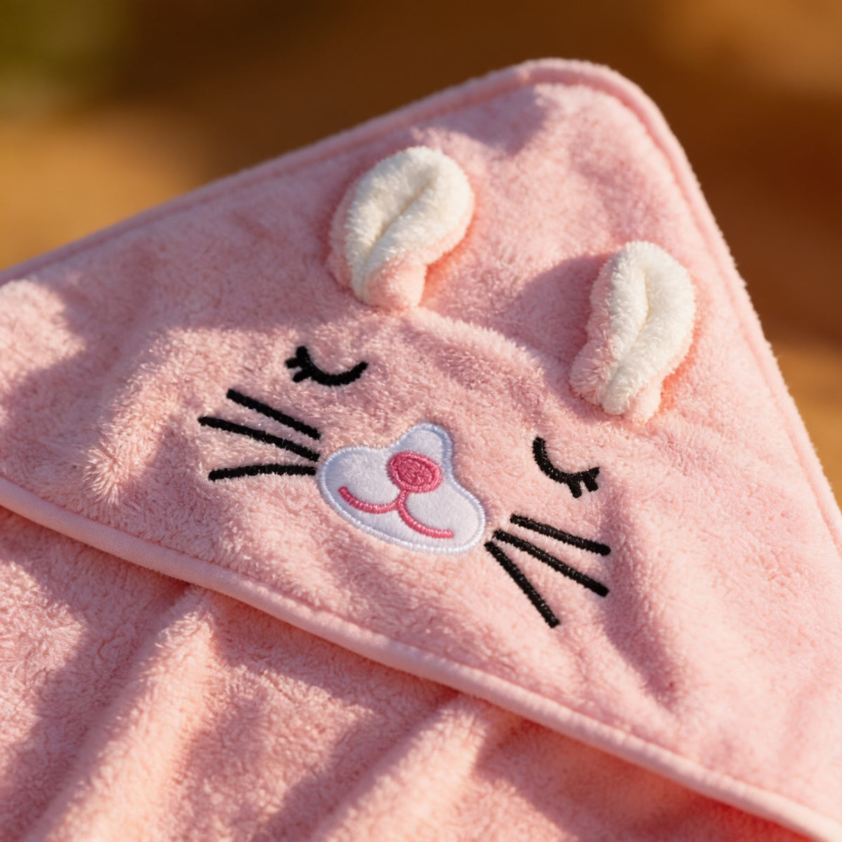 Close detail of the pink bunny hood's embroidered face and ears.