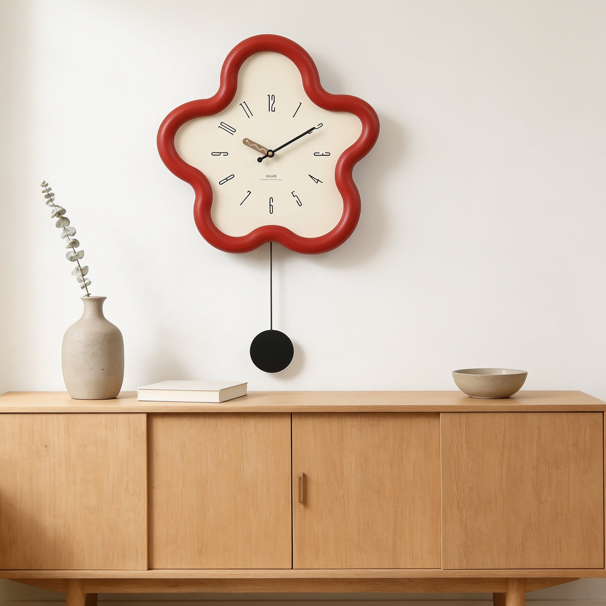 Red flower-shaped wall clock with swing pendulum above an oak sideboard — Wavy Flower-Shaped Wall Clock