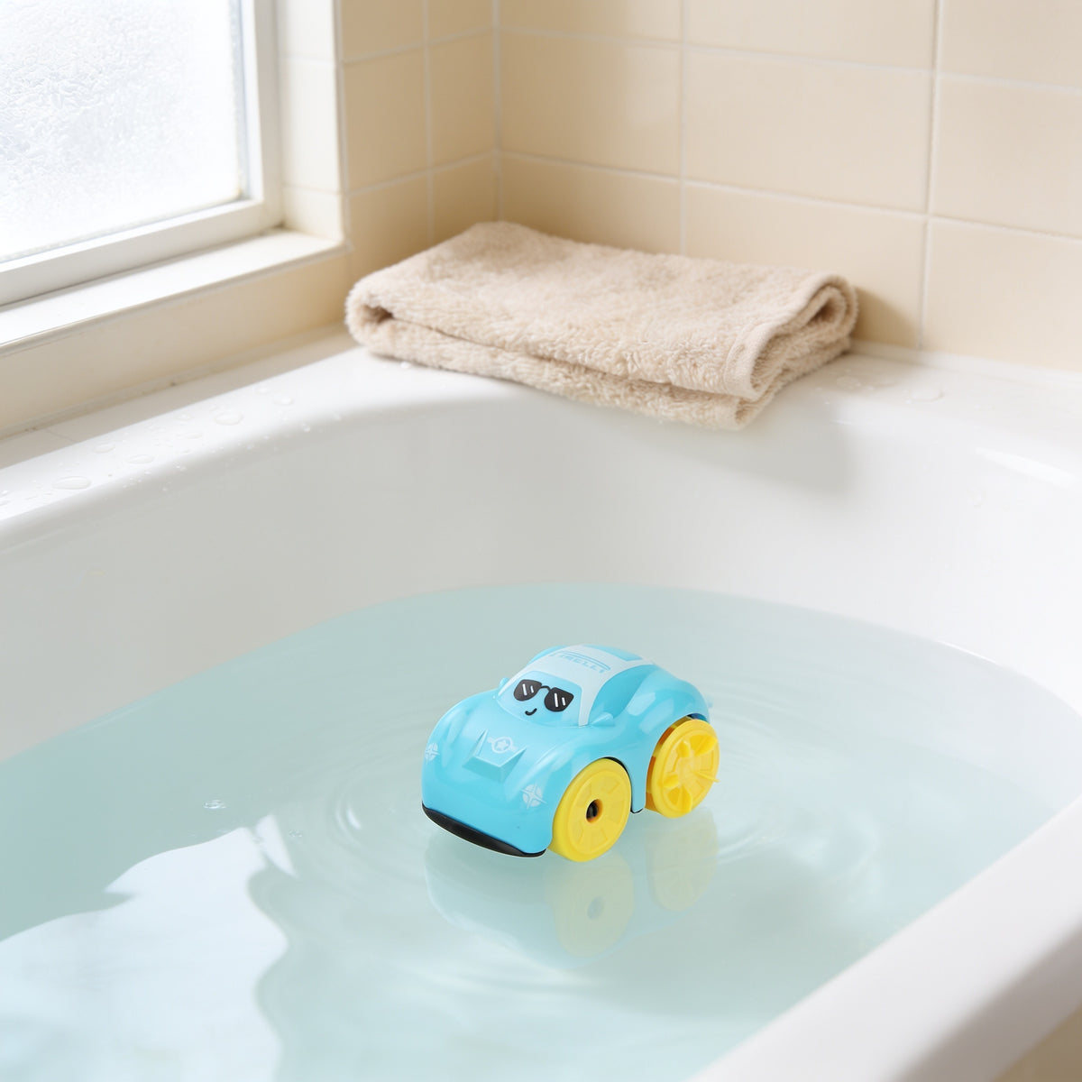 Light blue wind-up car bath toy floating on clear water in a white bathtub