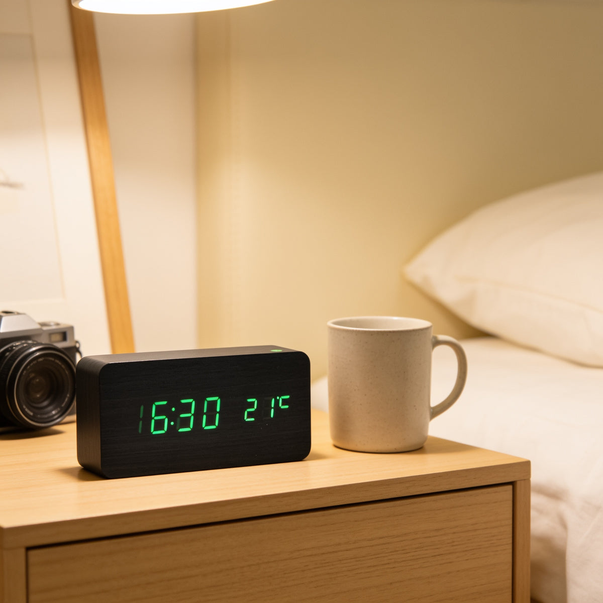 Black LED digital alarm clock with green digits on a bedside table