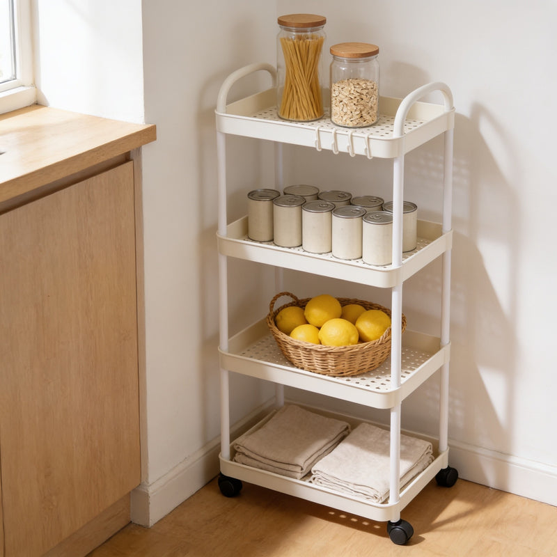 White four-tier rolling utility cart beside a kitchen counter, holding jars, cans, lemons and tea towels.