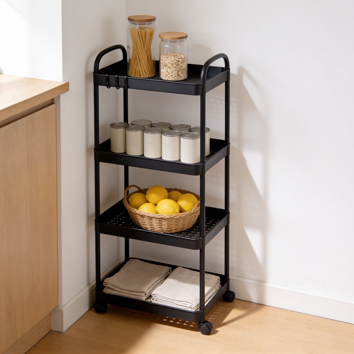 Black four-tier rolling utility cart in a kitchen corner.