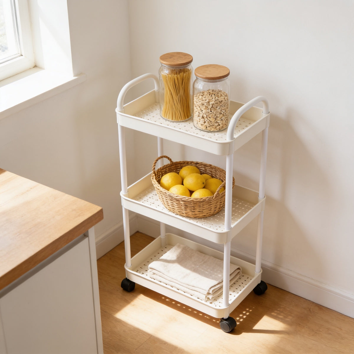 White three-tier rolling utility cart in a kitchen corner.