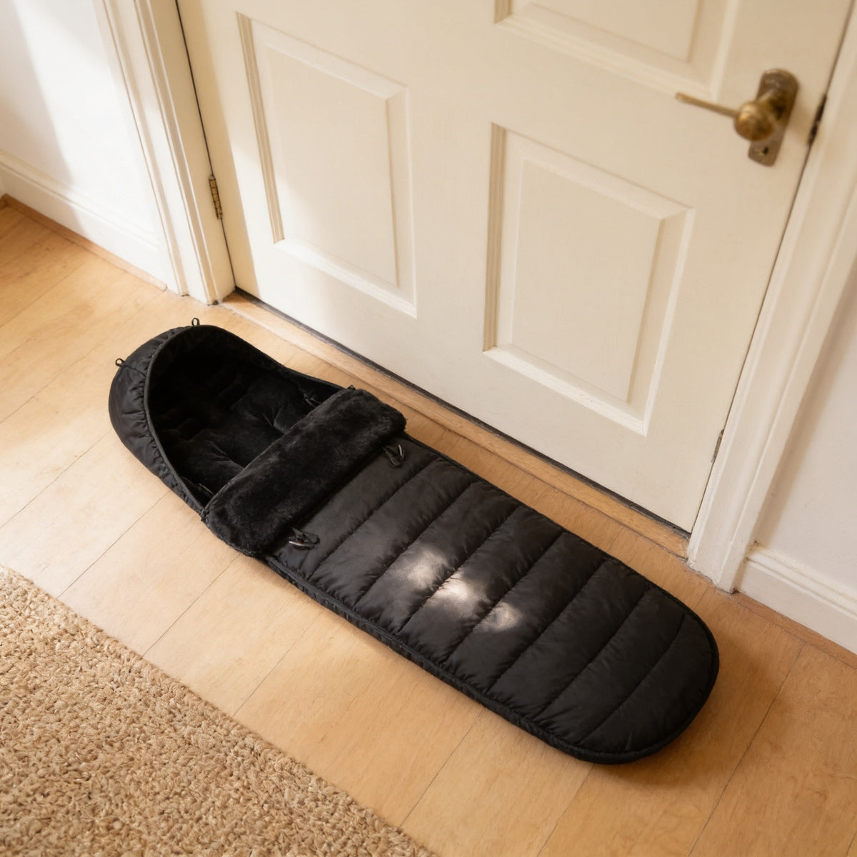 Black bunting bag lying flat in front of a front door, about as long as the door is wide at 90 cm.